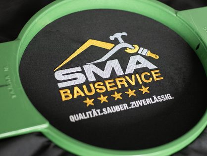 Probestick des SMA Bauservice Logos im Stickrahmen &ndash; Textilveredelung von hdw.media